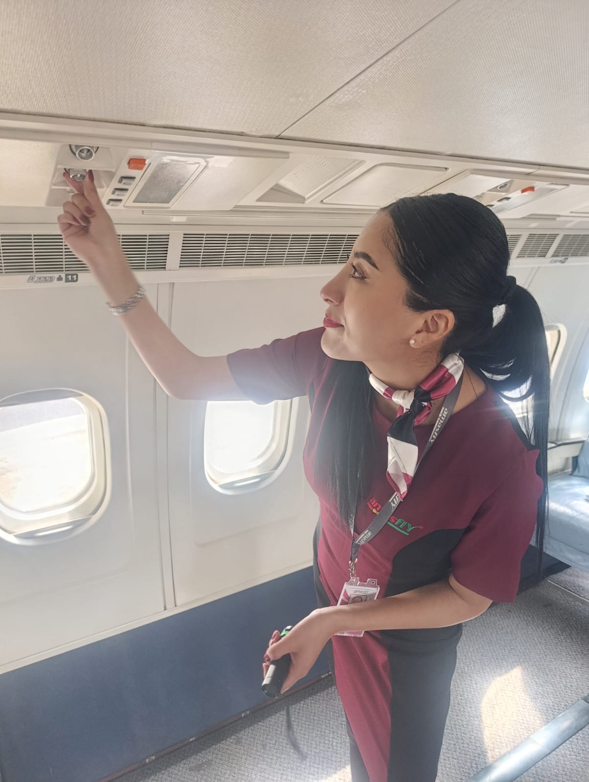 Instructora de AMASFLY señalando equipamiento en la cabina de pasajeros